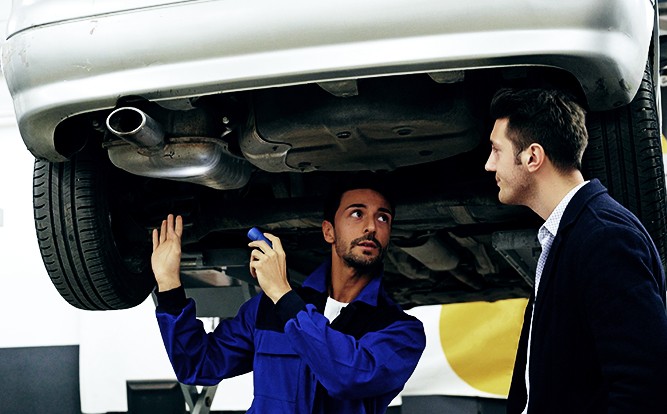 Mechanic-Customer-Talking-Under-Raised-Car